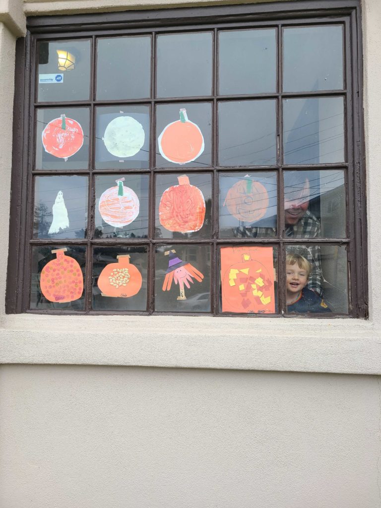 a large window on the side of a house displaying several monoprints of orange pumpkins