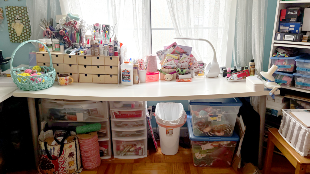 Worktable filled with craft supplies with bins underneath.