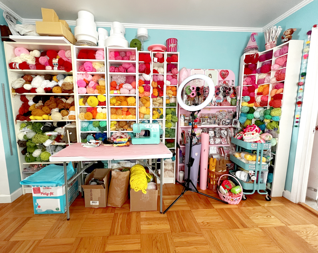 Craft room wall with bookshelves of colorful yarn and craft supplies.