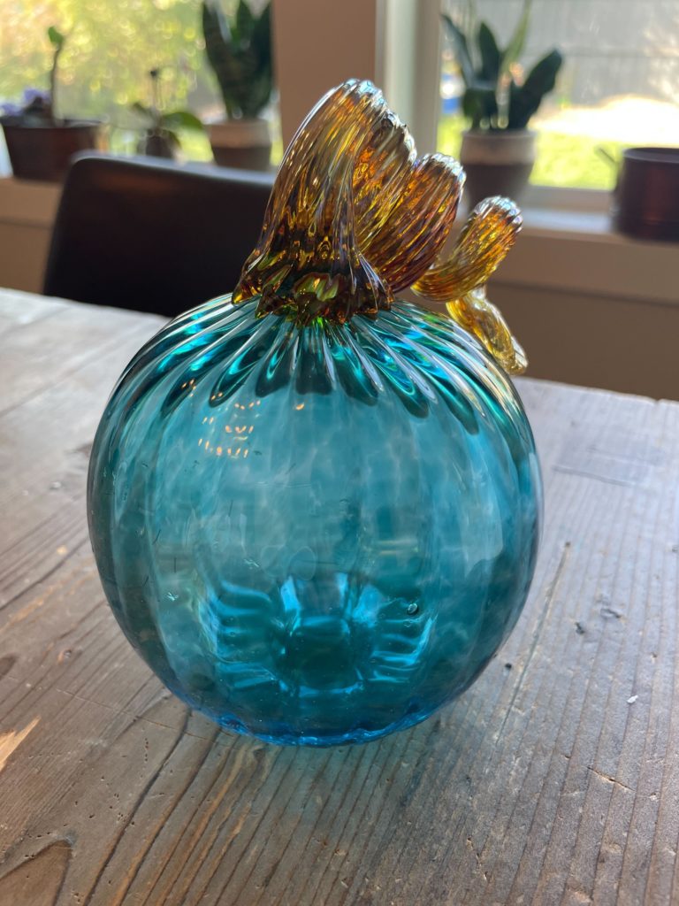 blue pumpkin made from handblown glass on a wooden table