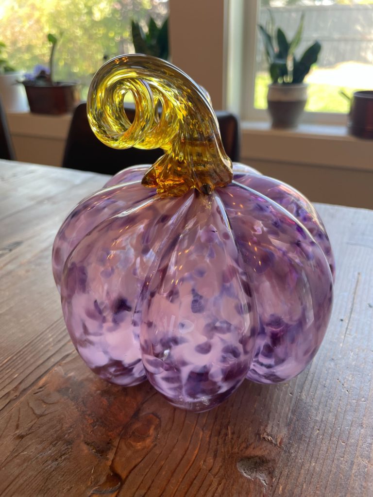 lavender pumpkin made from handblown glass on a wooden table
