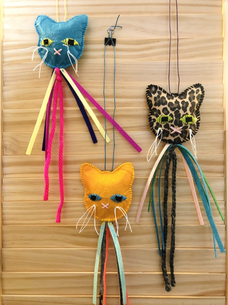 three handmade felt catnip toys in different prints and colors, shaped like cat heads