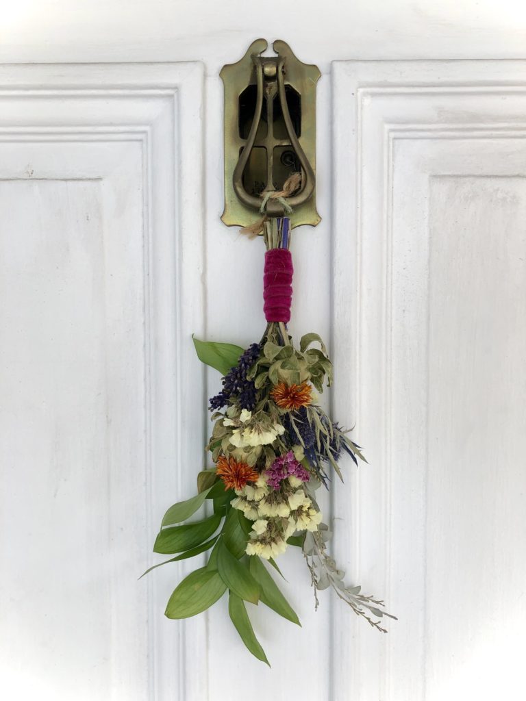 a fresh flower bough hanging on a white door