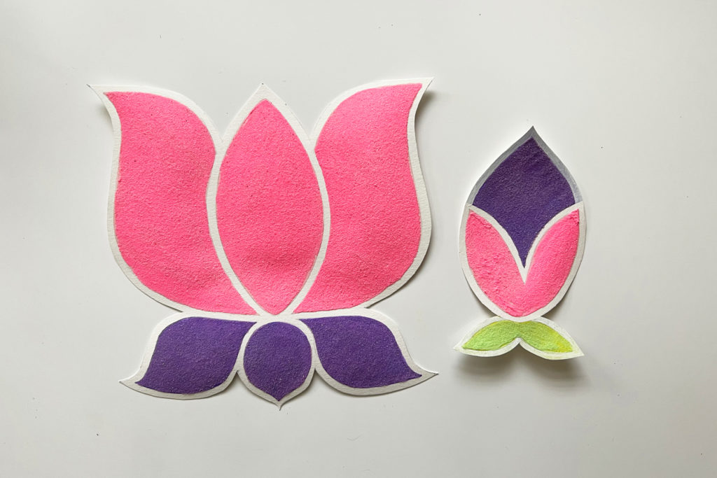 flat lay on a white background of two pieces of and art for rangoli: a large pink and purple lotus flower and a smaller pink, purple, and green lotus bd
