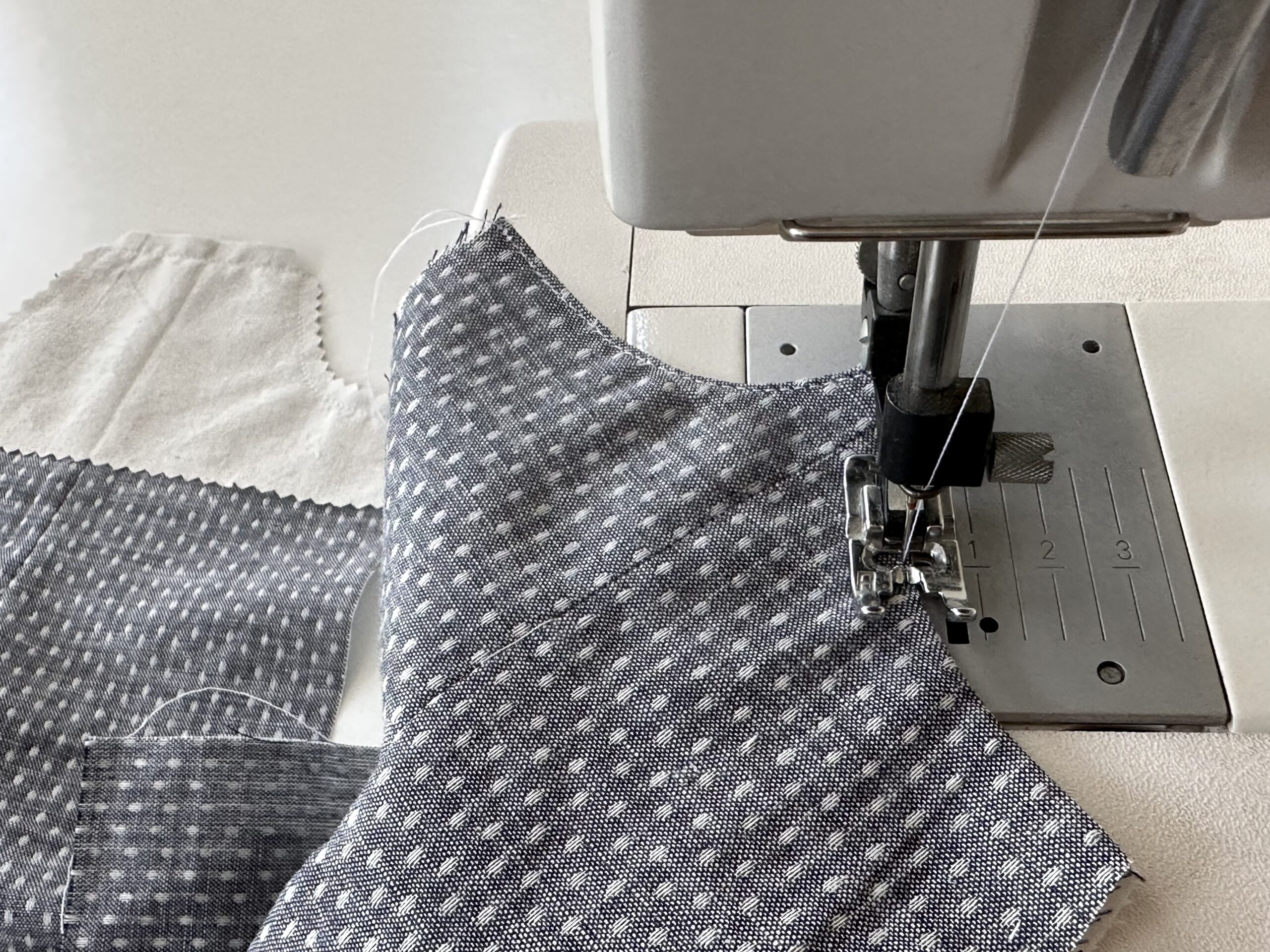 image of grey fabric pieces being sewn in a sewing machine for doll clothing