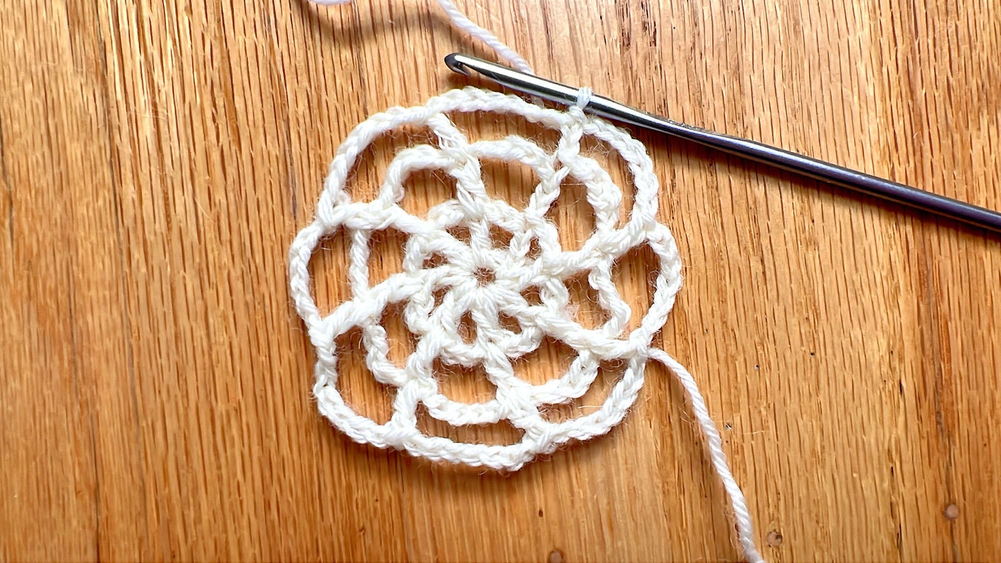 image of circular crochet project worked in ivory yarn on a wood floor