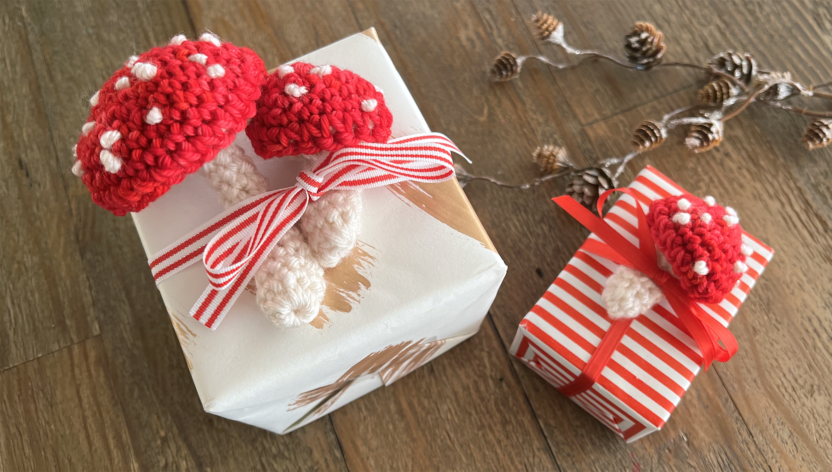 image of small red and white crocheted mushrooms on top of gift boxes warpped in red and white paper