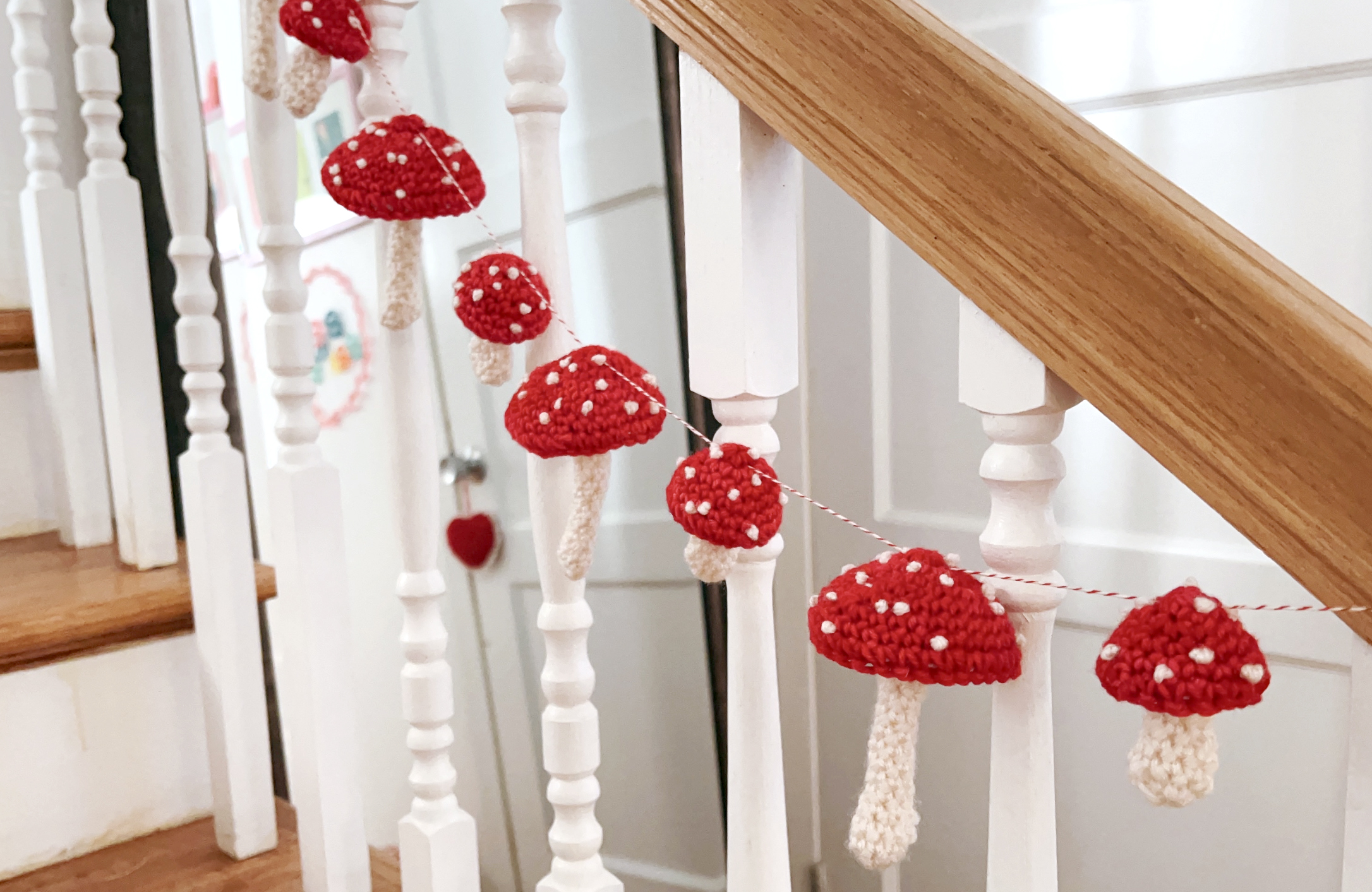 image of red and white toadstool garland hanging from a wooden banister