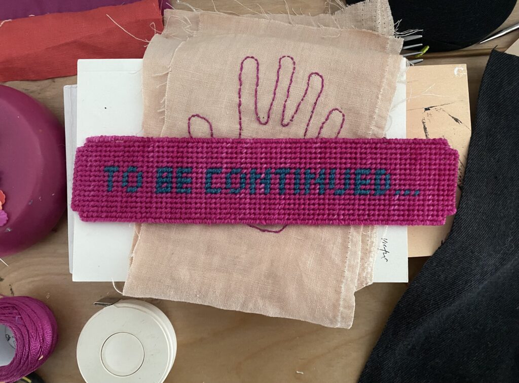 images of needlepoint bookmark with purple background and dark blue text that reads "To be continued..."