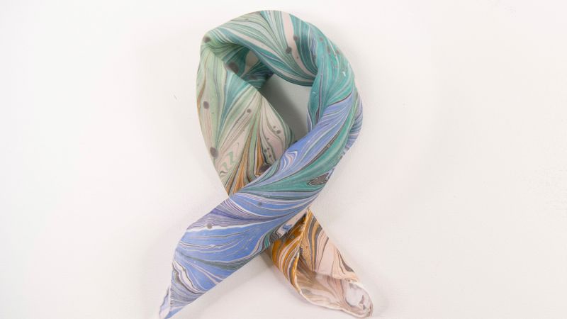 image of a lightly twisted silk scarf that has been decorated with a marbled paint design