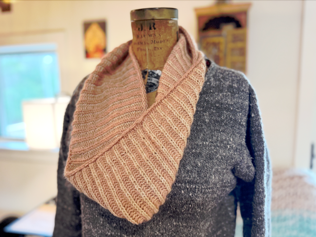 image of dress form wearing a grey knit sweater and a brioche knit peach-colored cowl