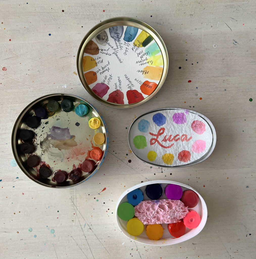 image of mini watercolor kits in tins with small circles of pigment arranged in rainbow order