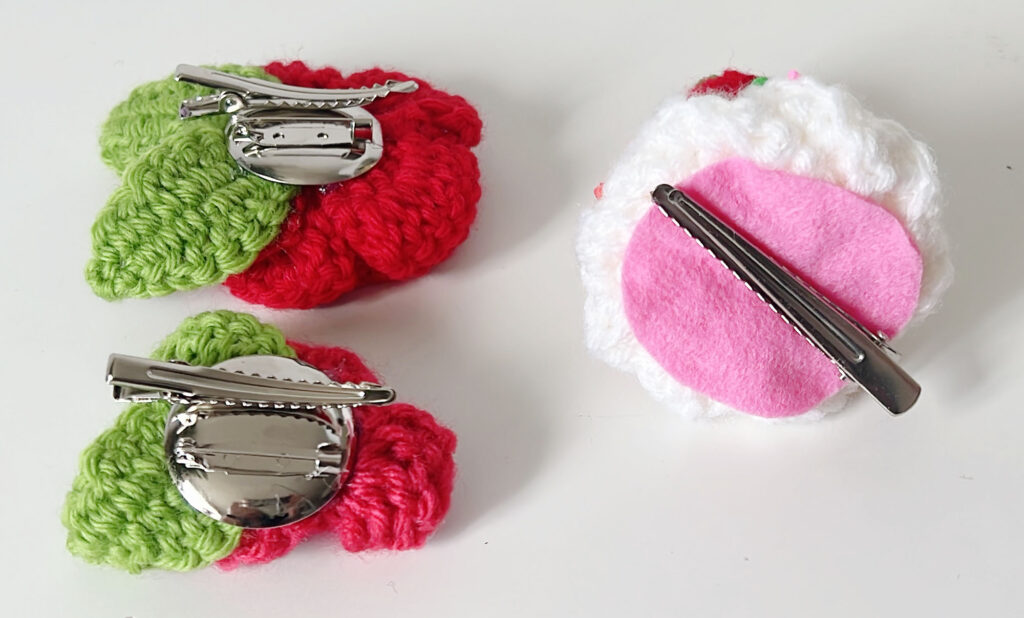 images of 3 crocheted hair clips - 2 roses and one whipped cream dollop - turned to show the metal pin backs and hair clips